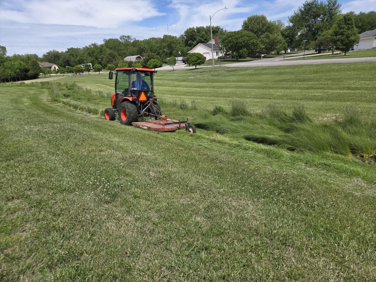 City employee mowing the central park waterway with the Bush Hog