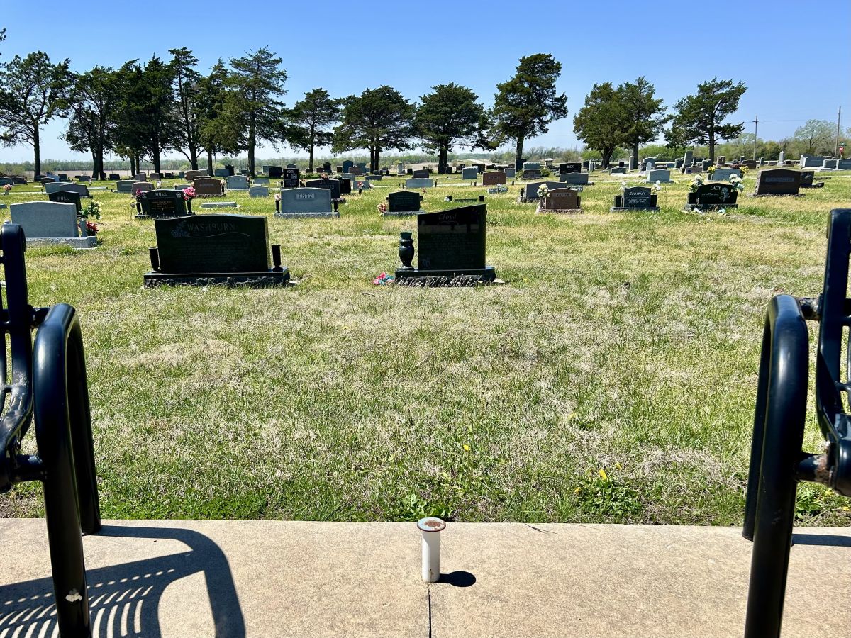 multiple stones in view with trees in the background looking west through the cemetery