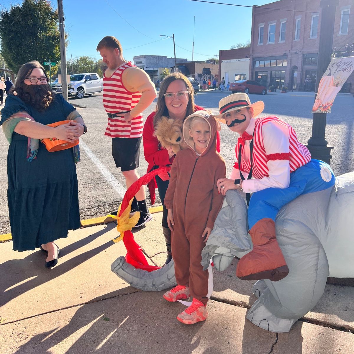 Bank employees with a trick or treater, all smiles on a sunny day